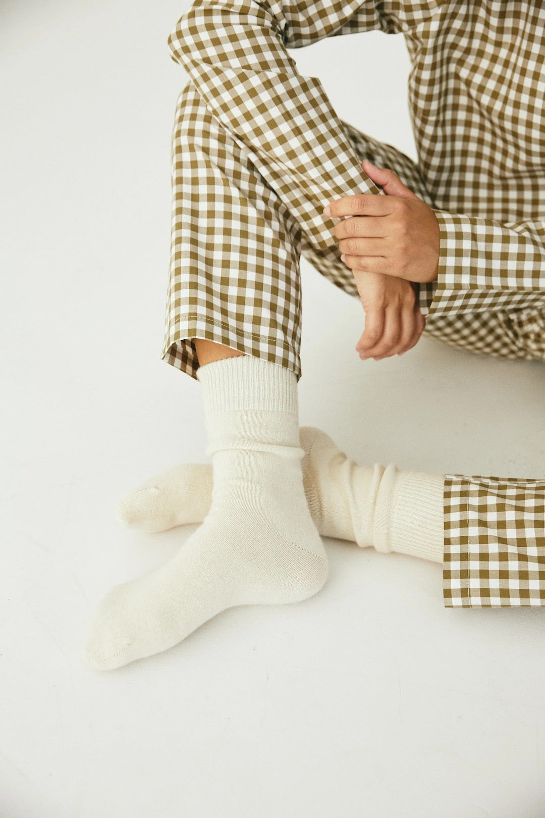 A woman wearing the Classic Set - Olive Gingham by general sleep, including a plaid shirt and socks.