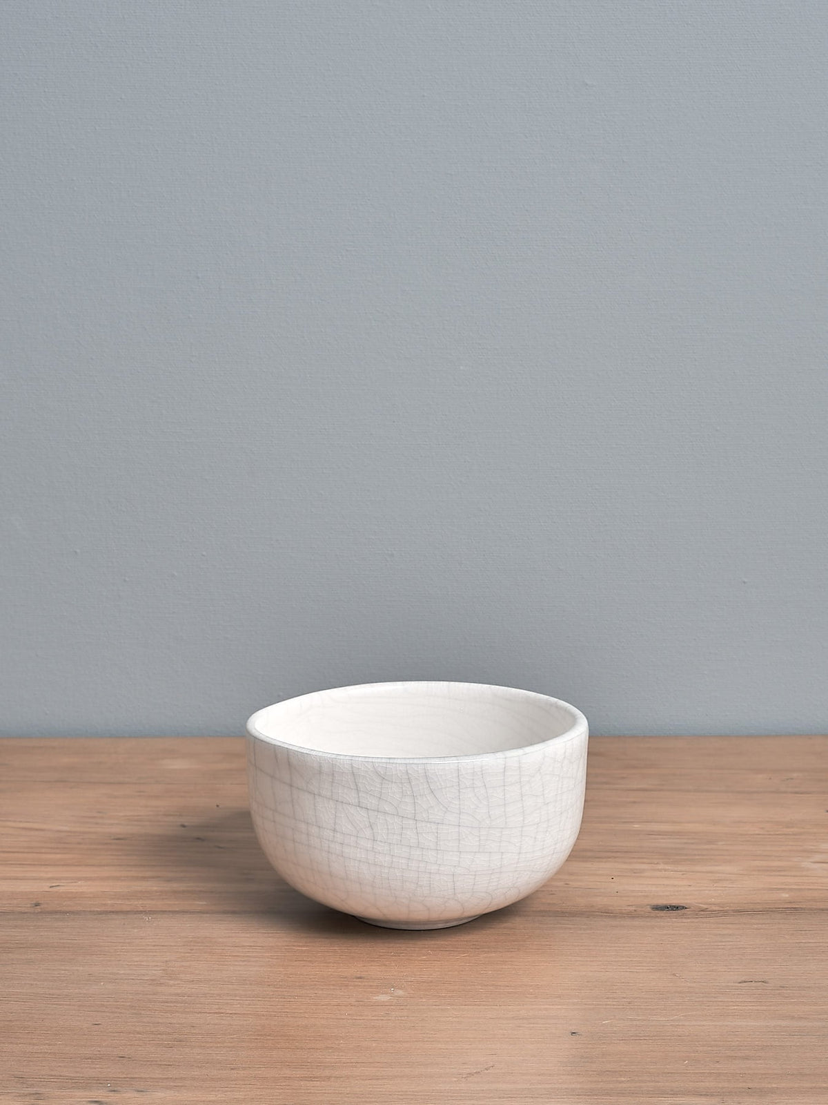 An Olive Bowl – Bone Crackle by Gidon Bing sitting on top of a wooden table.