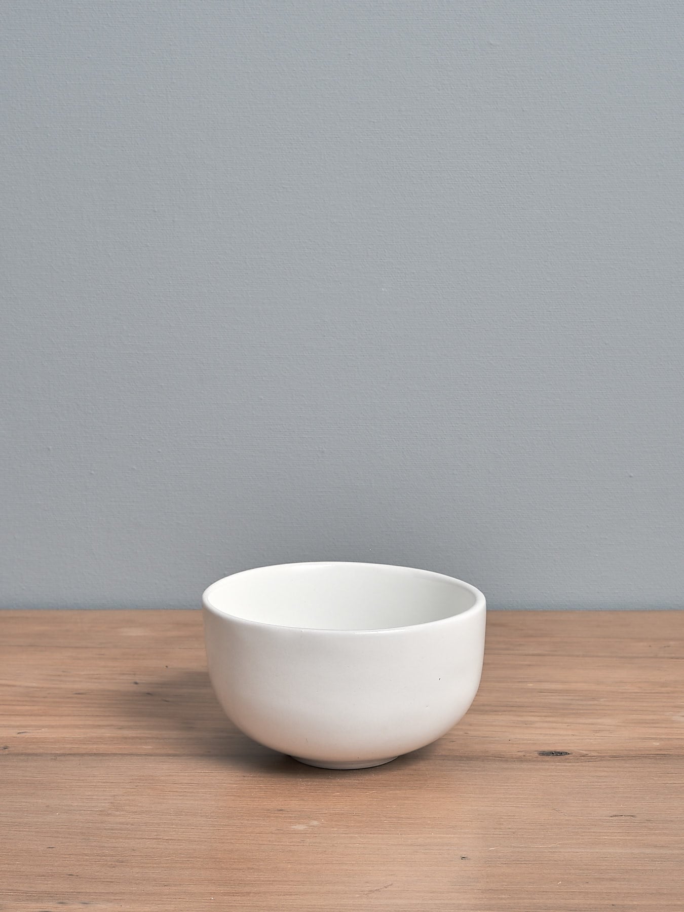 An Olive Bowl – Satin White by Gidon Bing sitting on a wooden table.