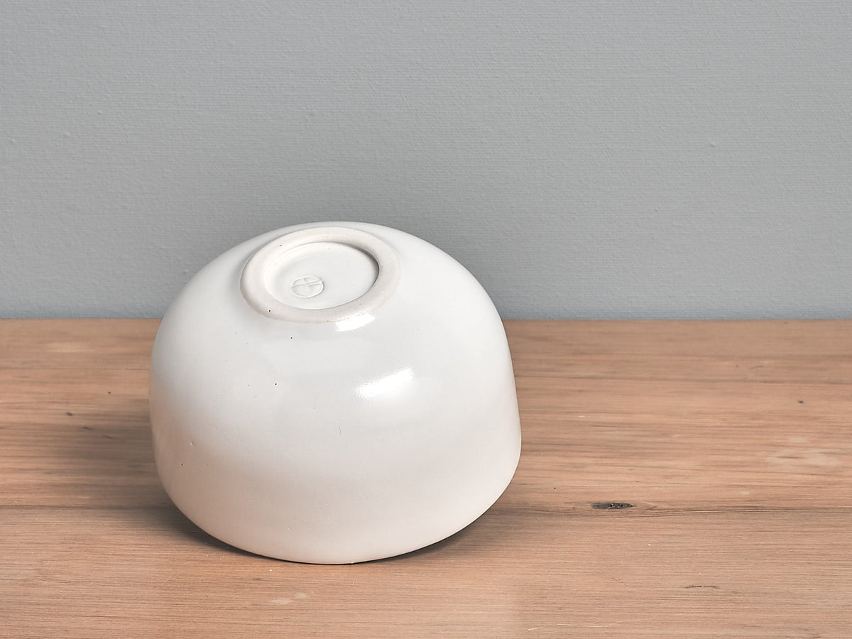 An Olive Bowl – Satin White by Gidon Bing sitting on top of a wooden table.