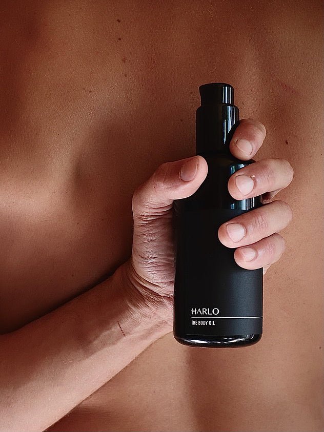 A man holding a bottle of Harlo body oil.
