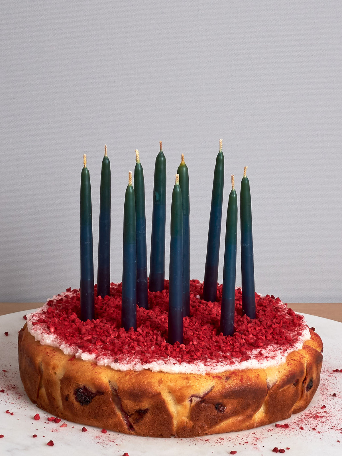 A cake with Hohepa Birthday Candles Set – Green, Blue &amp; Purple on top of it.