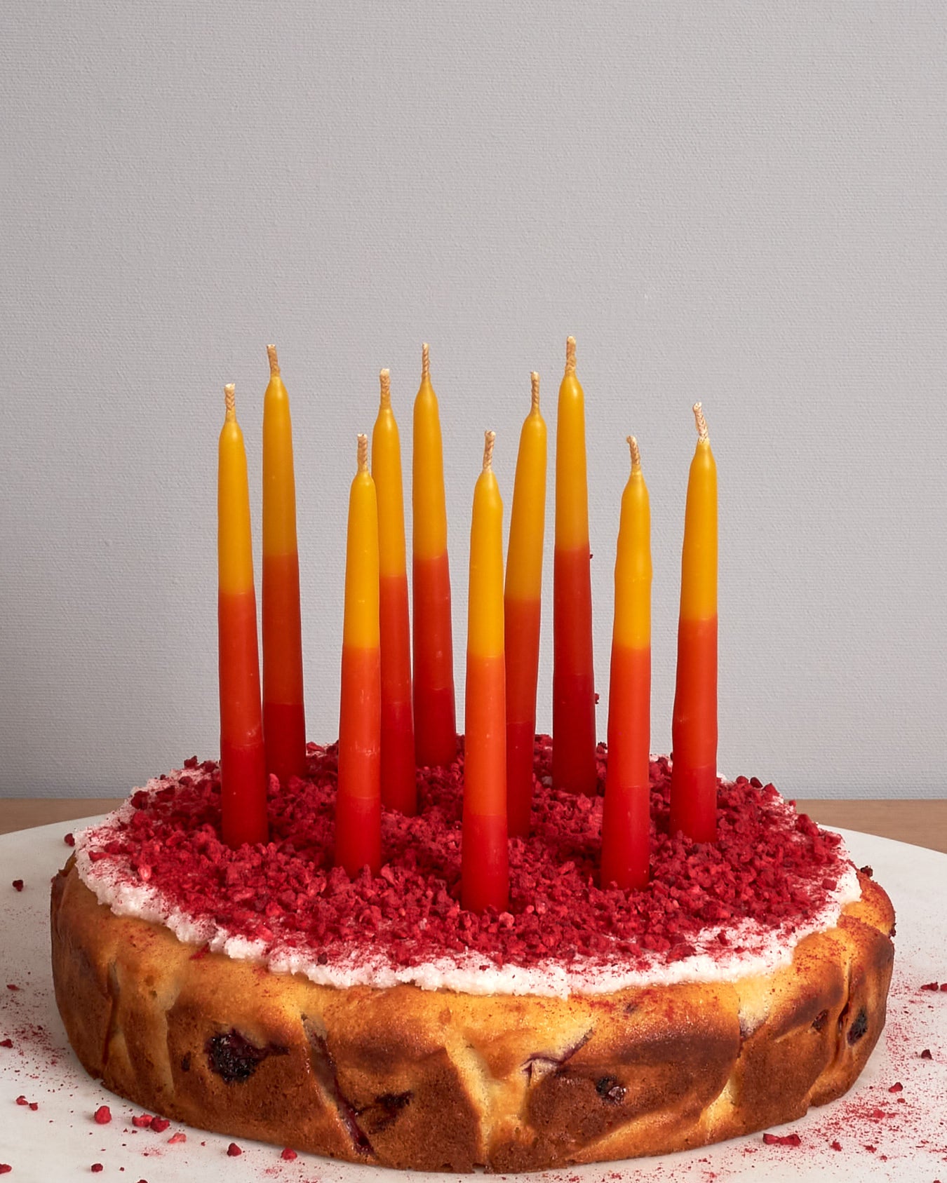 A Hohepa Candles Birthday Candles Set - Red, Orange & Yellow on a wooden table.