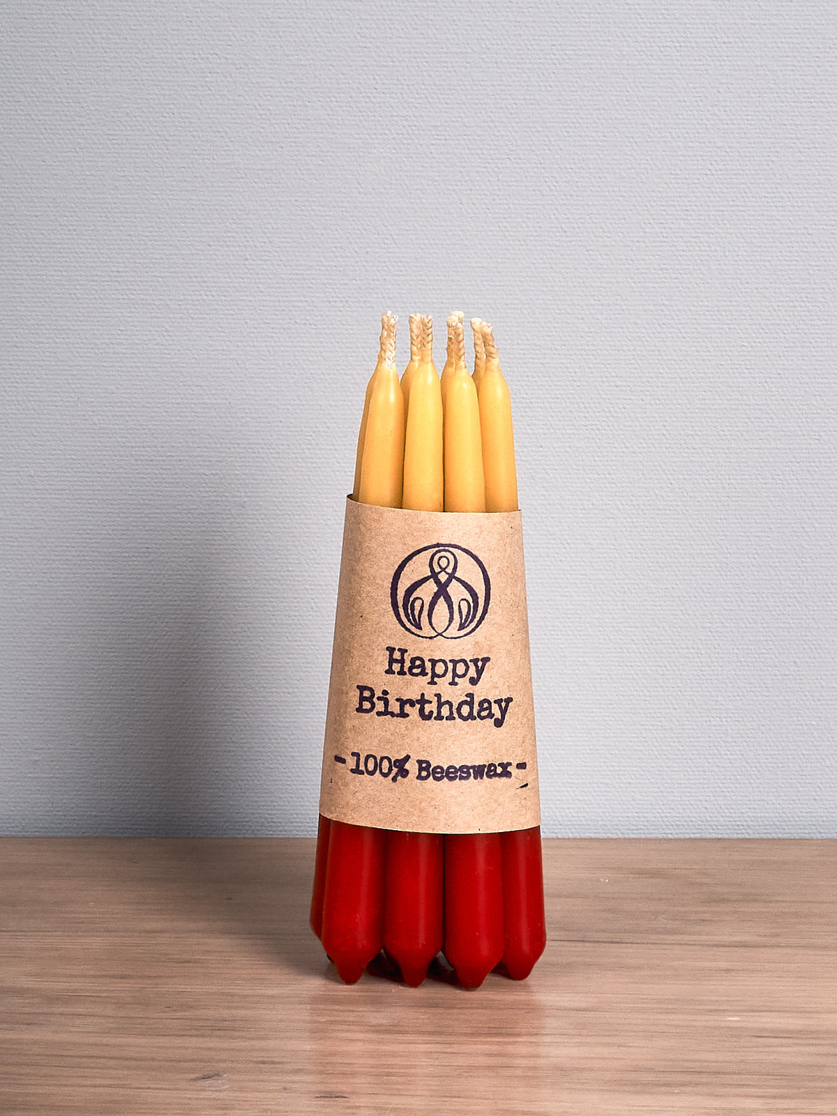 A Hohepa Candles Birthday Candles Set - Red, Orange &amp; Yellow on a wooden table.