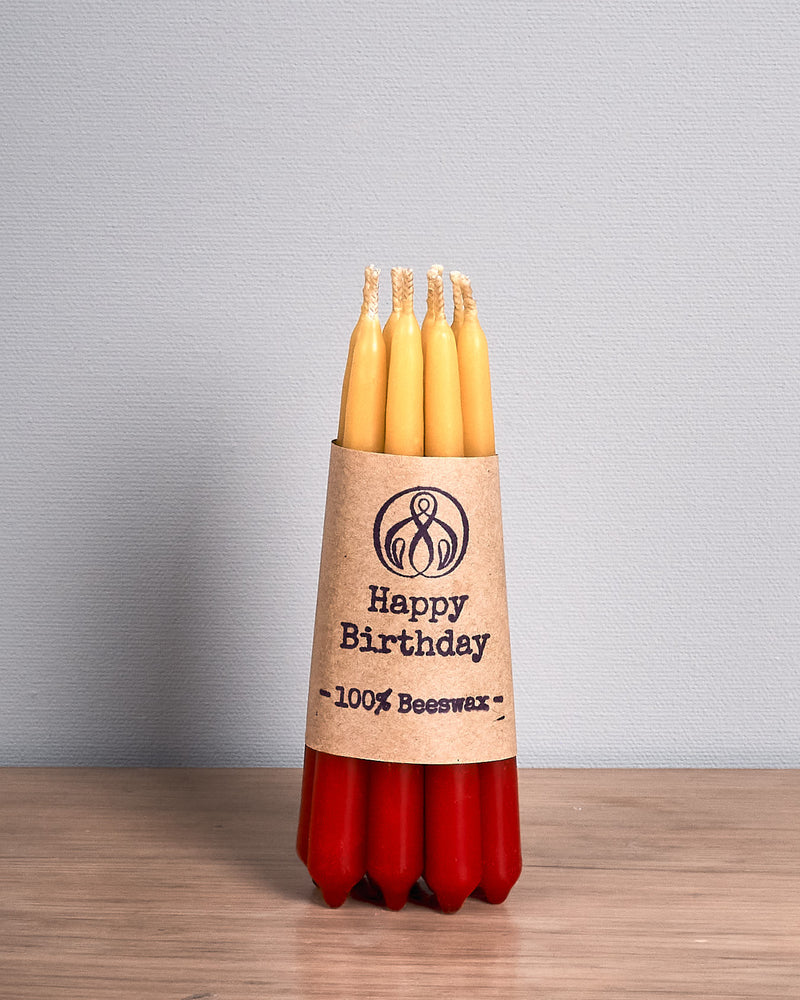 A Hohepa Candles Birthday Candles Set - Red, Orange & Yellow on a wooden table.