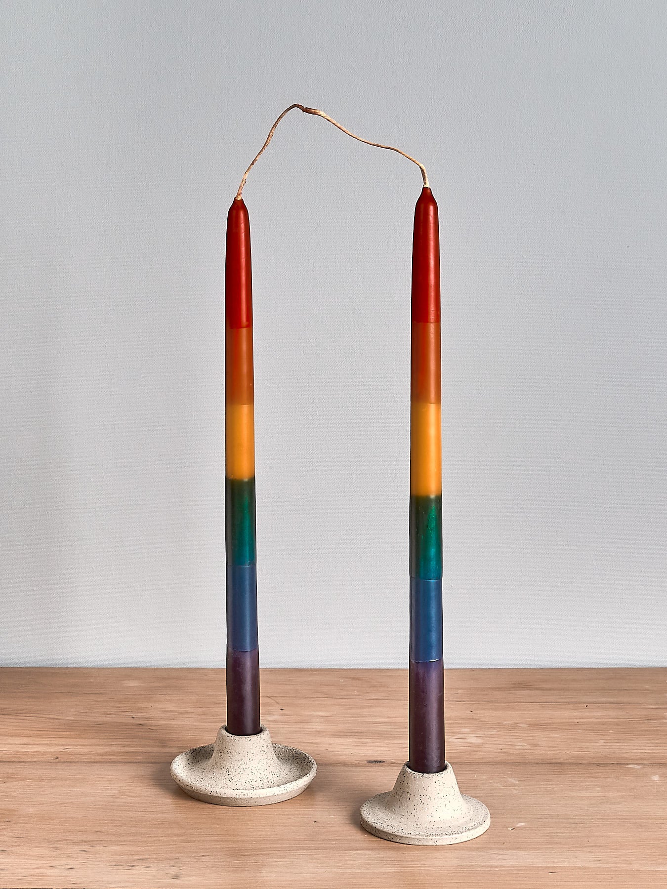 Two Dinner Candle Sets - Rainbow by Hohepa Candles on a wooden table.