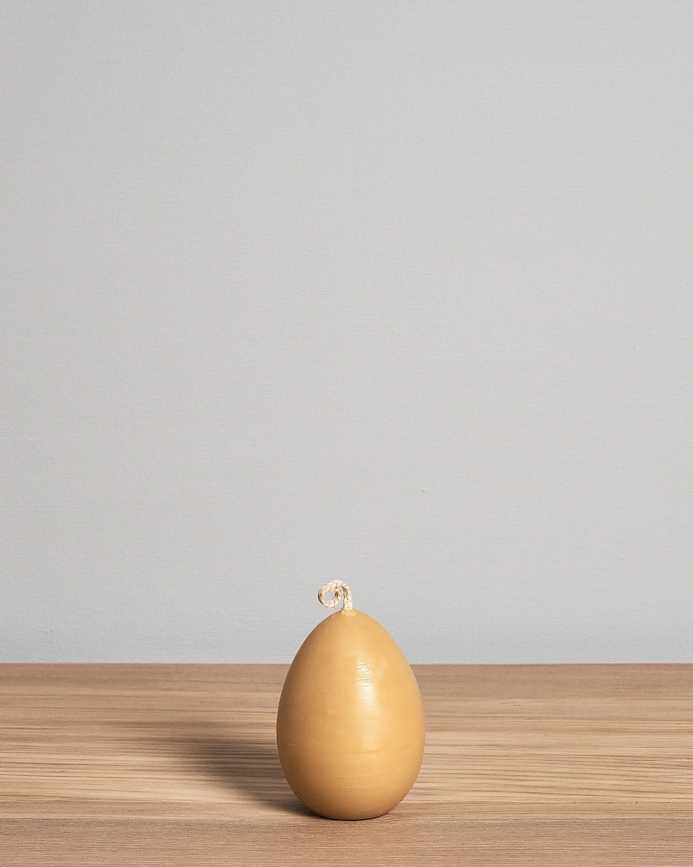 A yellow Hohepa Candles egg sitting on a wooden table.