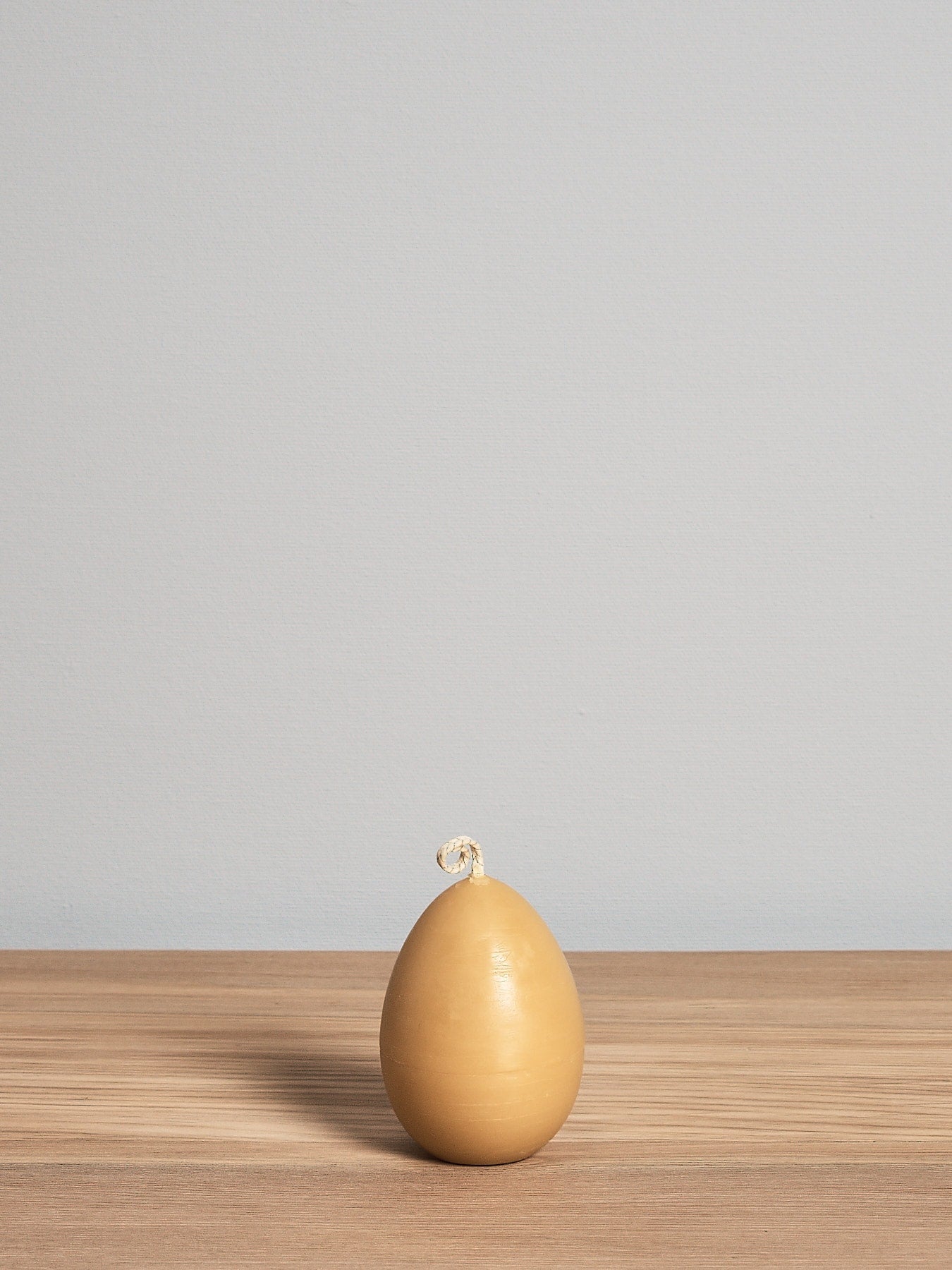 A yellow Hohepa Candles egg sitting on a wooden table.