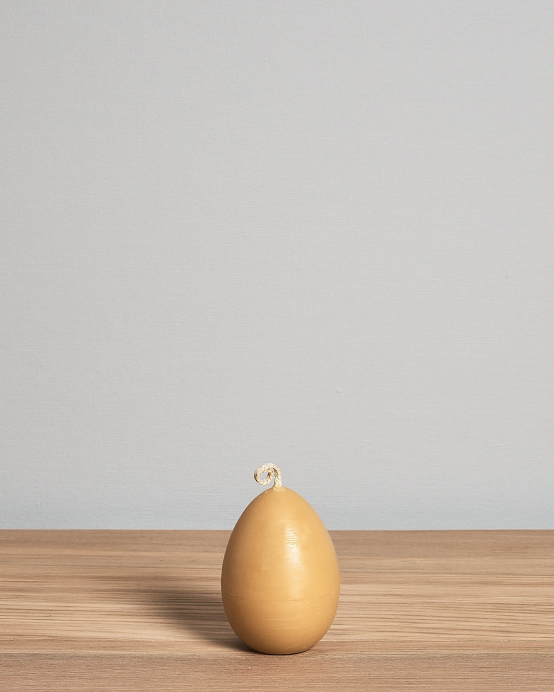 A yellow Hohepa Candles egg sitting on a wooden table.