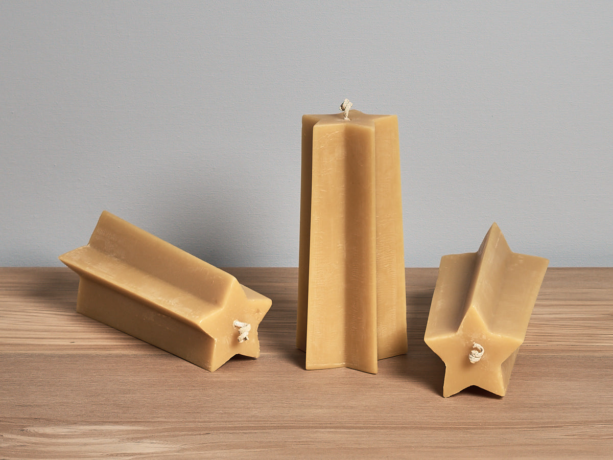 Three Star Pillar Candles by Hohepa Candles on a wooden table.