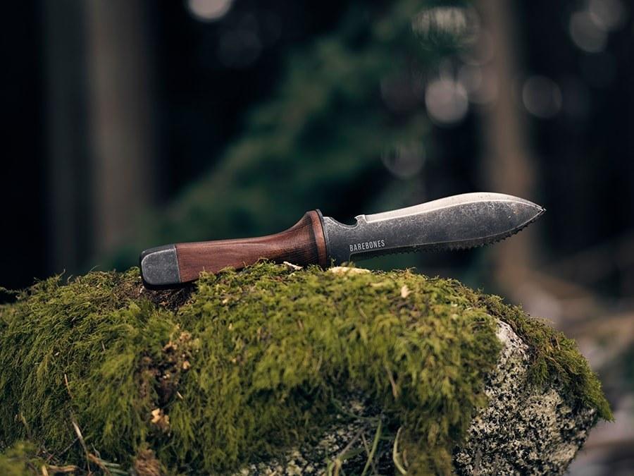 A Hori Hori Garden Knife &amp; Sheath by Barebones sitting on top of moss in the woods.