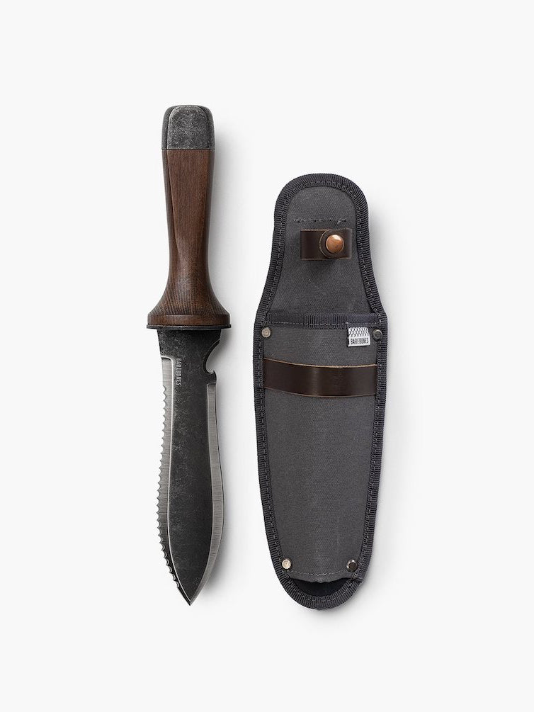 A Hori Hori Garden Knife &amp; Sheath by Barebones with a leather sheath on a white surface.