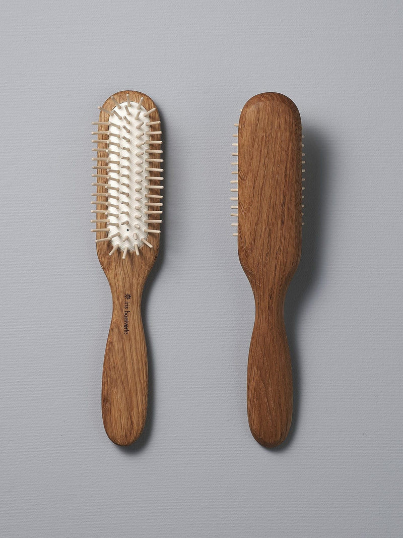 Two Iris Hantverk Oak Hairbrushes with smooth handles, one showing the bristles side with natural rubber pins and the other the back, positioned side by side on a gray background. Perfect for a soothing scalp massage.