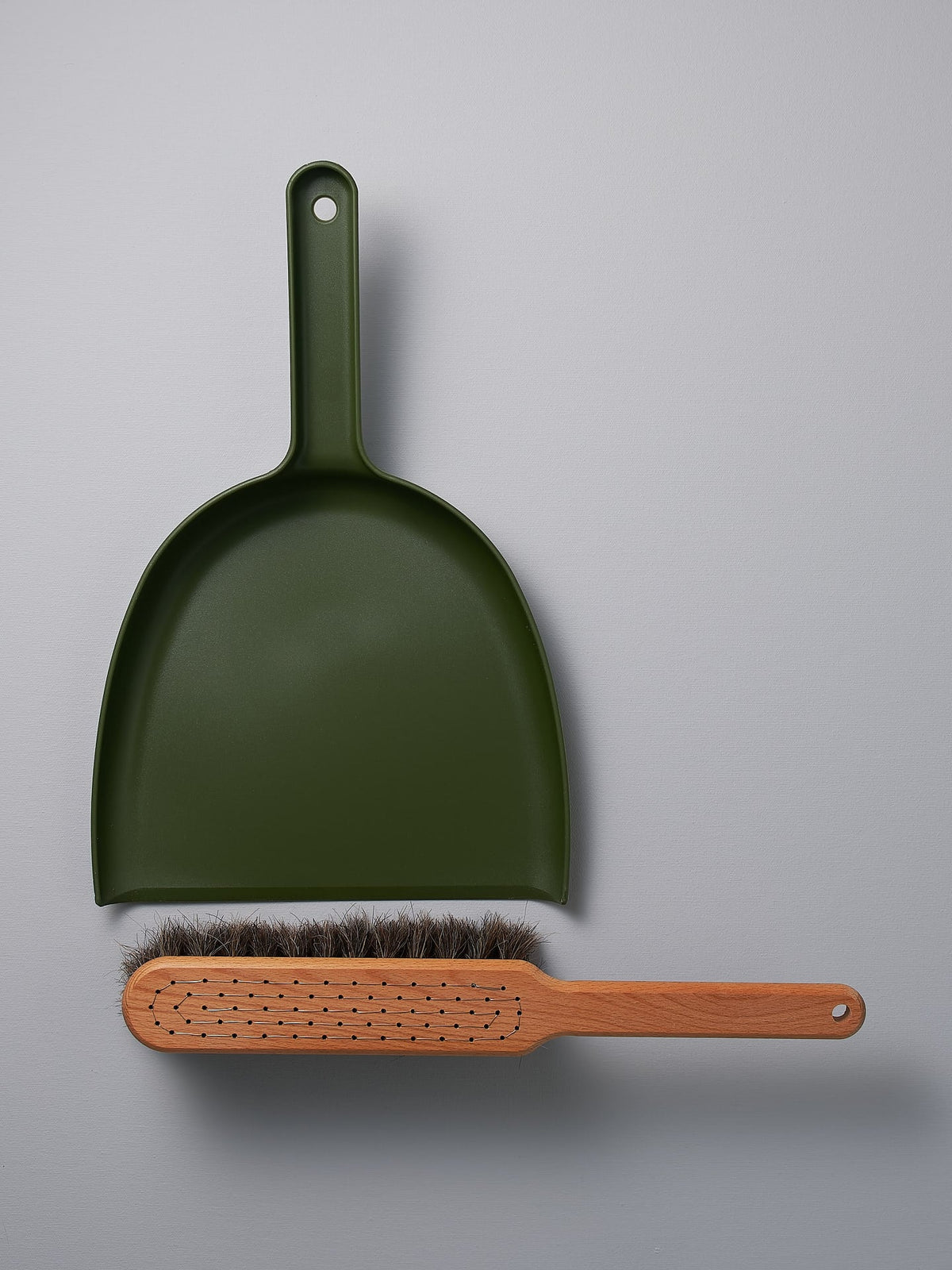 A Dustpan &amp; Brush Set – Moss Green by Iris Hantverk on a grey surface.