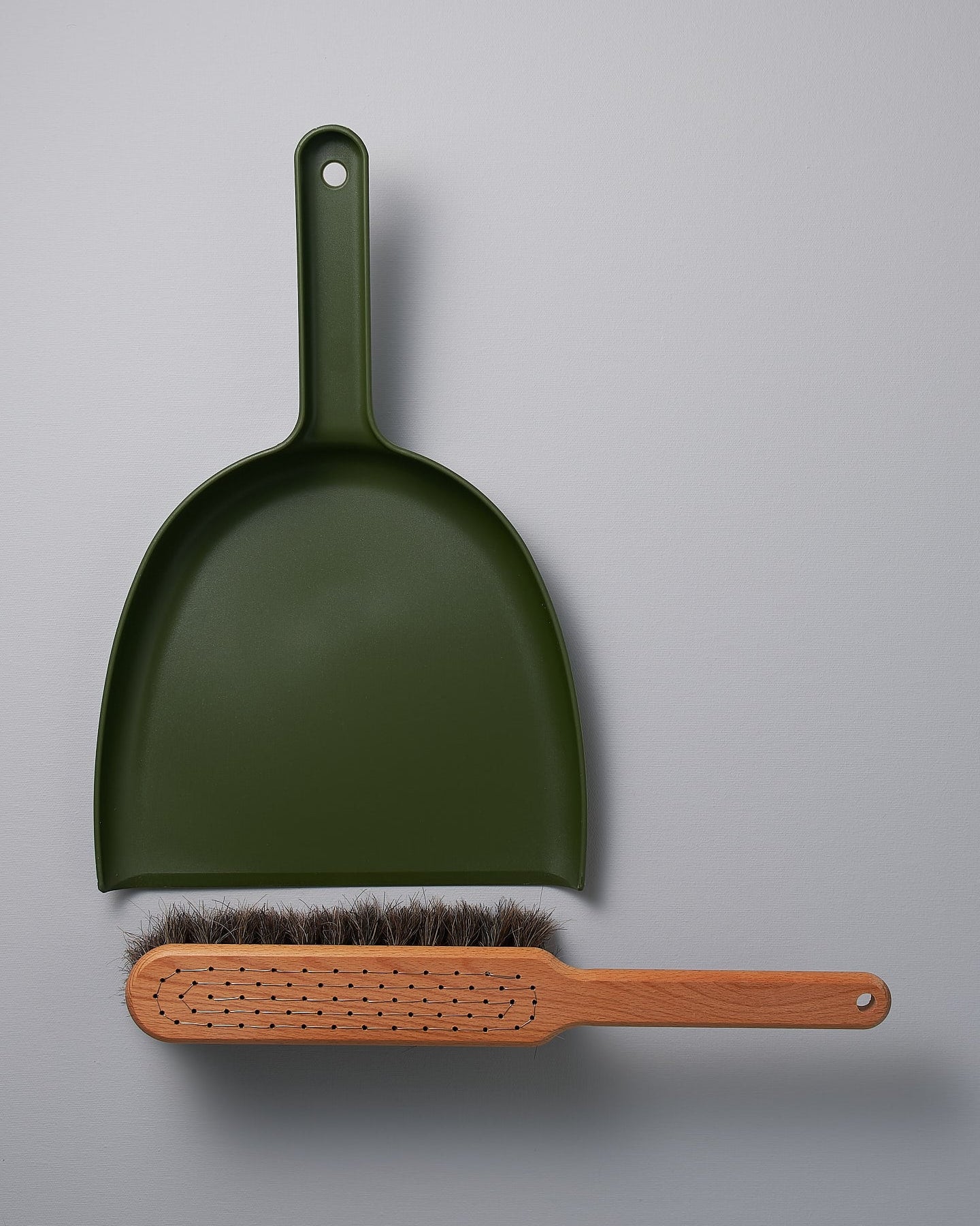 A Dustpan & Brush Set – Moss Green by Iris Hantverk on a grey surface.