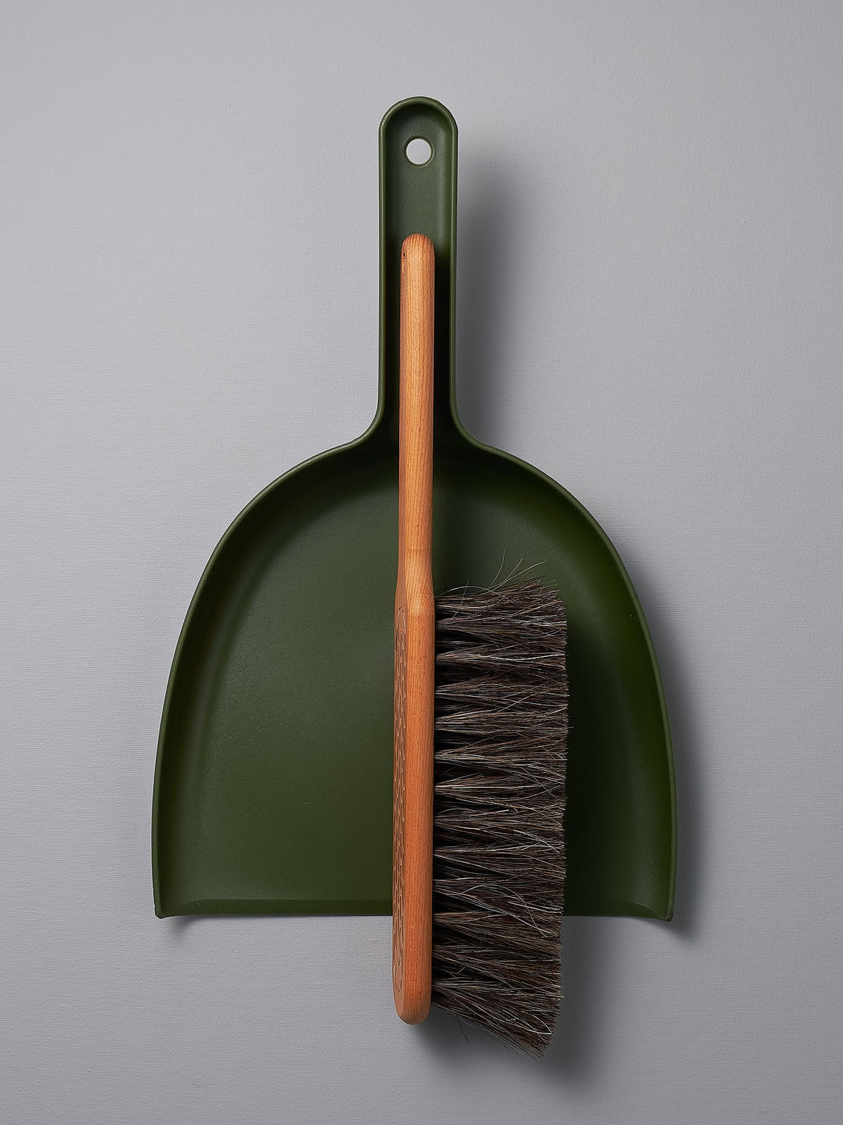 An Iris Hantverk Dustpan &amp; Brush Set – Moss Green with a brush attached to it.