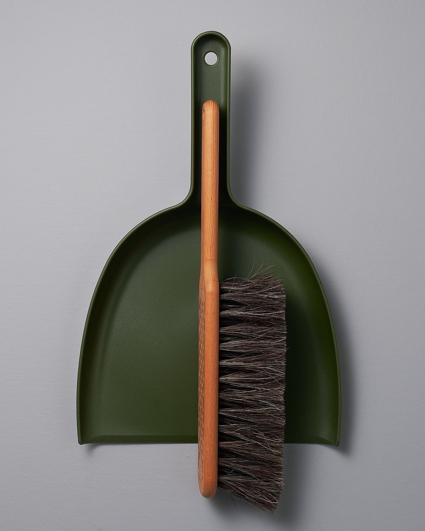 A Dustpan & Brush Set – Moss Green by Iris Hantverk on a grey surface.