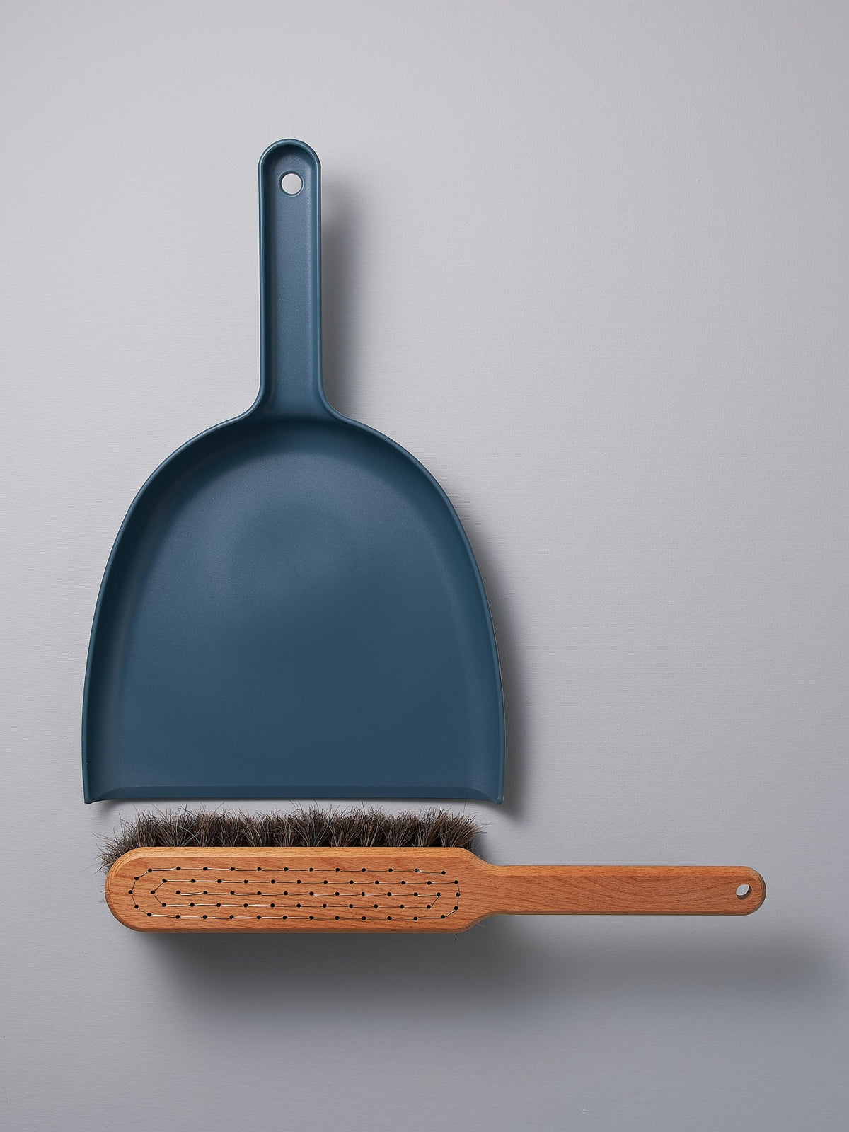 A Dustpan &amp; Brush Set – Petrol Blue by Iris Hantverk on a grey surface.