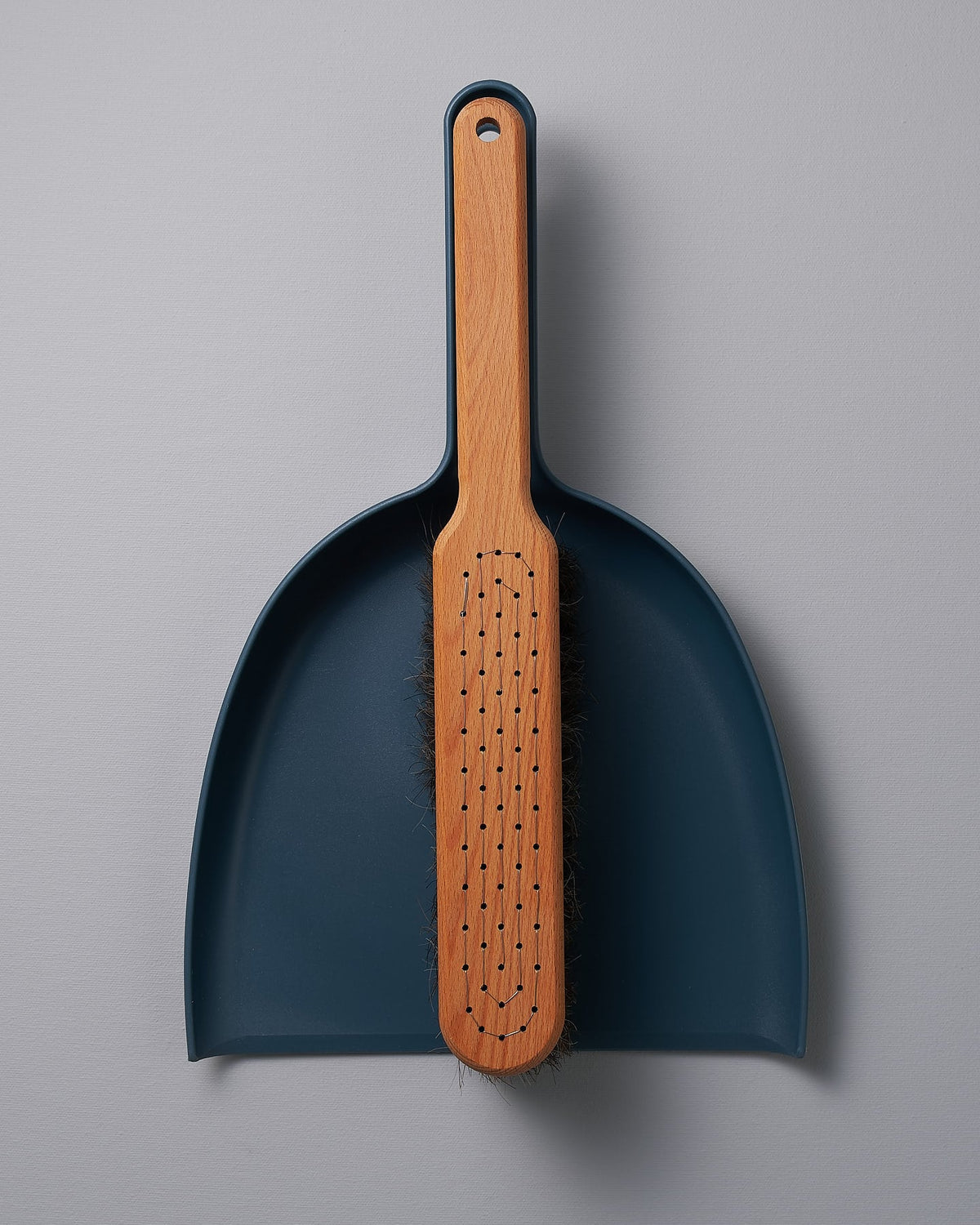 An Iris Hantverk Petrol Blue Dustpan & Brush Set with a wooden handle.