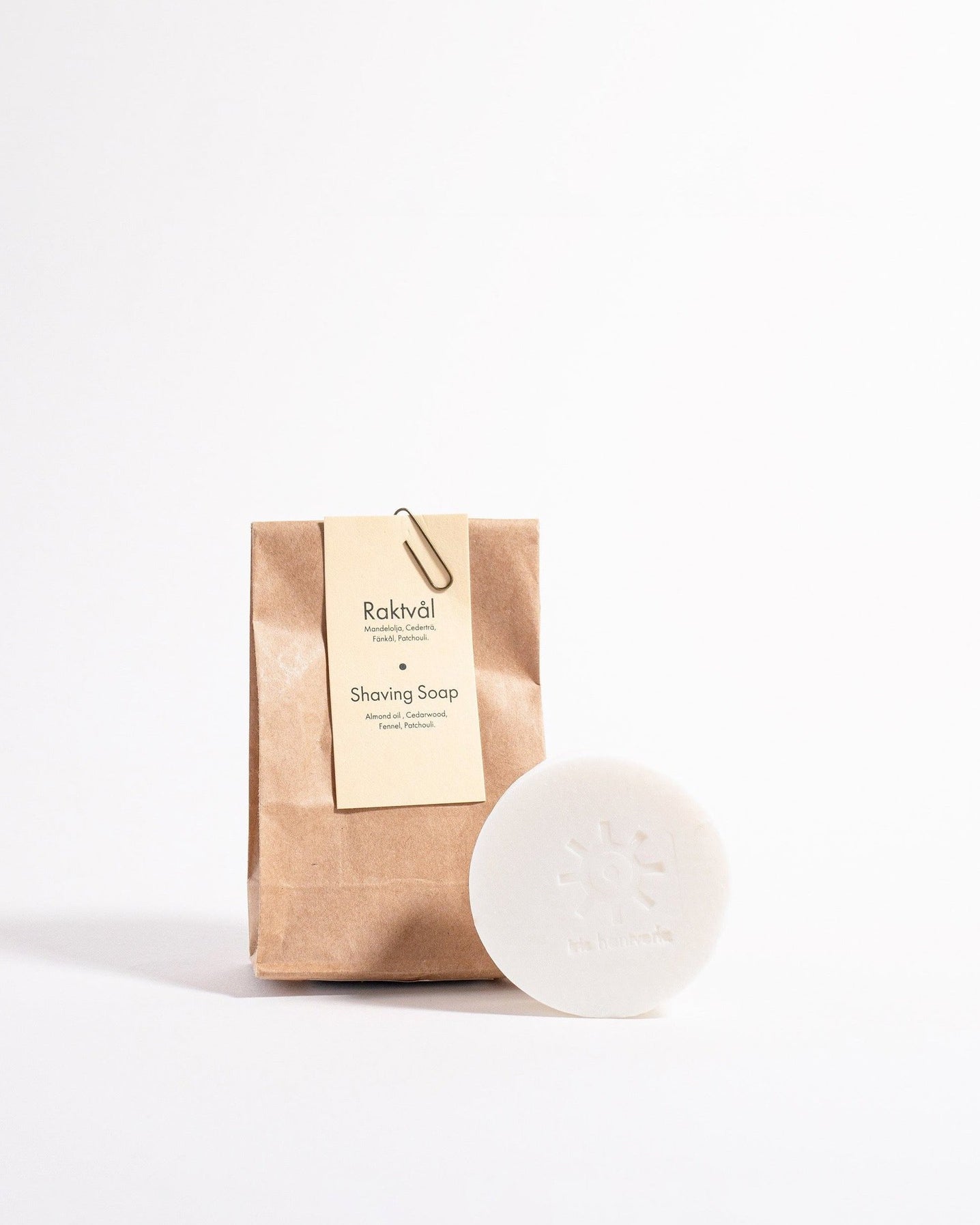 A bar of Iris Hantverk Shaving Soap – Cedarwood next to a brown paper bag.