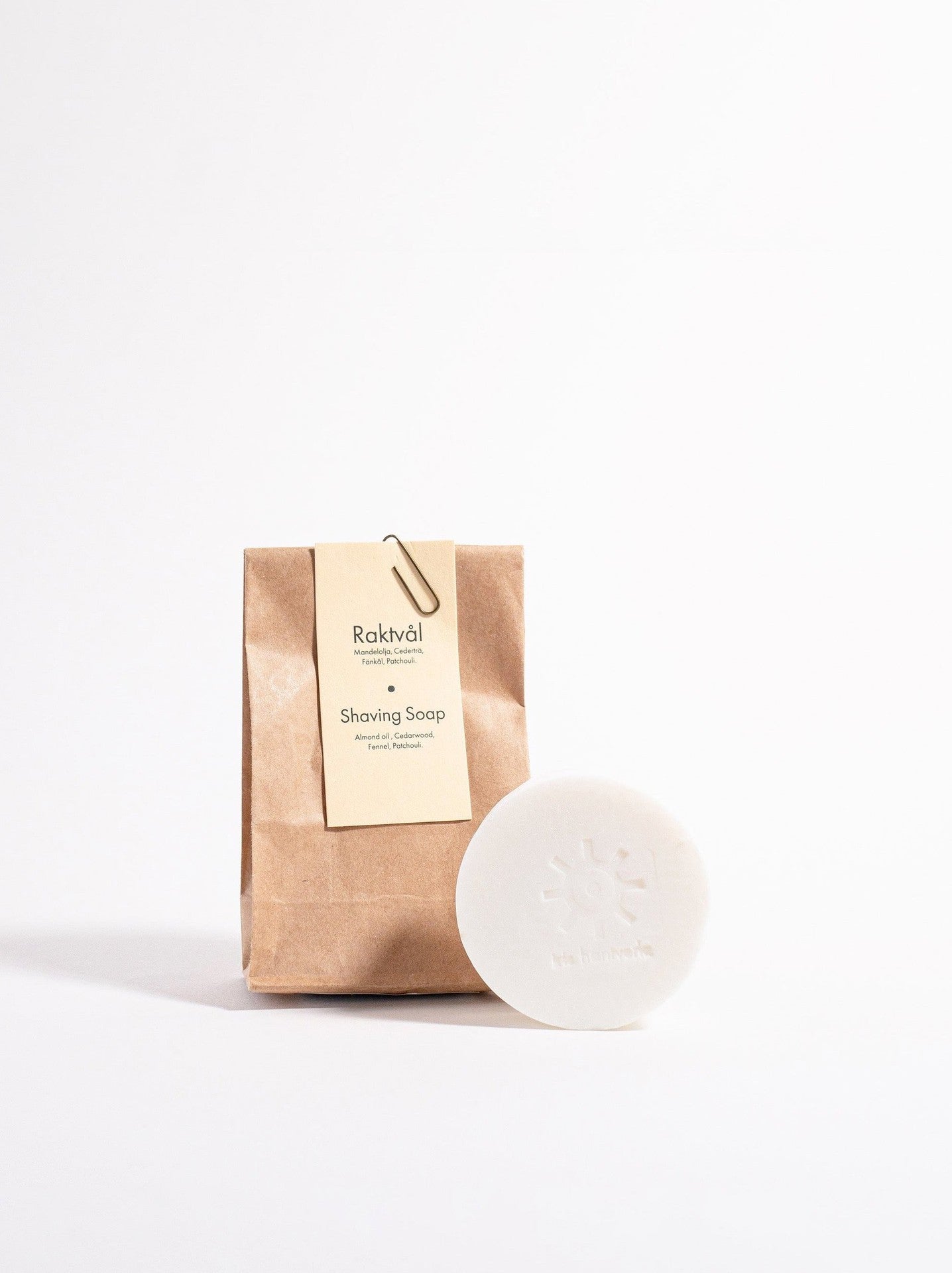 A bar of Iris Hantverk Shaving Soap – Cedarwood next to a brown paper bag.