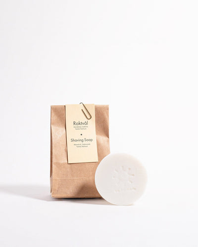 A bar of Iris Hantverk Shaving Soap – Cedarwood next to a brown paper bag.