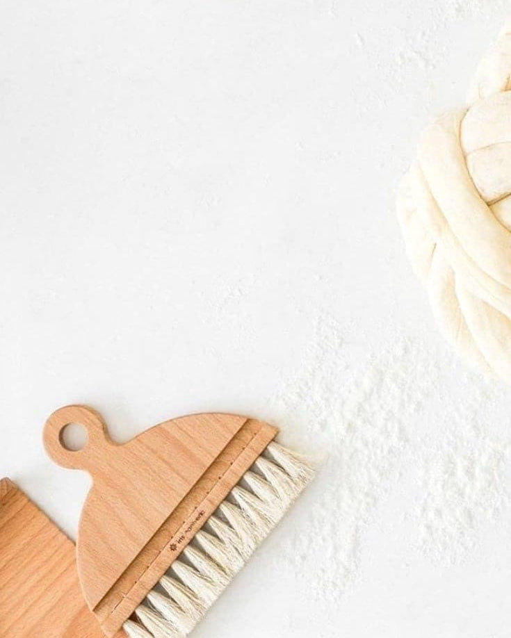 A bowl of flour and an Iris Hantverk Nesting Table Brush & Pan Set on a white surface.