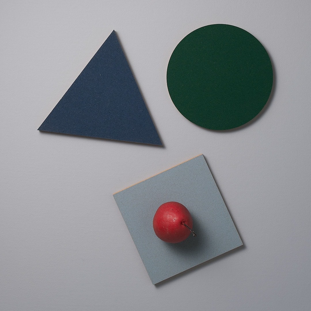 A Trivet - Racing Green sits on top of a blue, green, and red piece of paper.