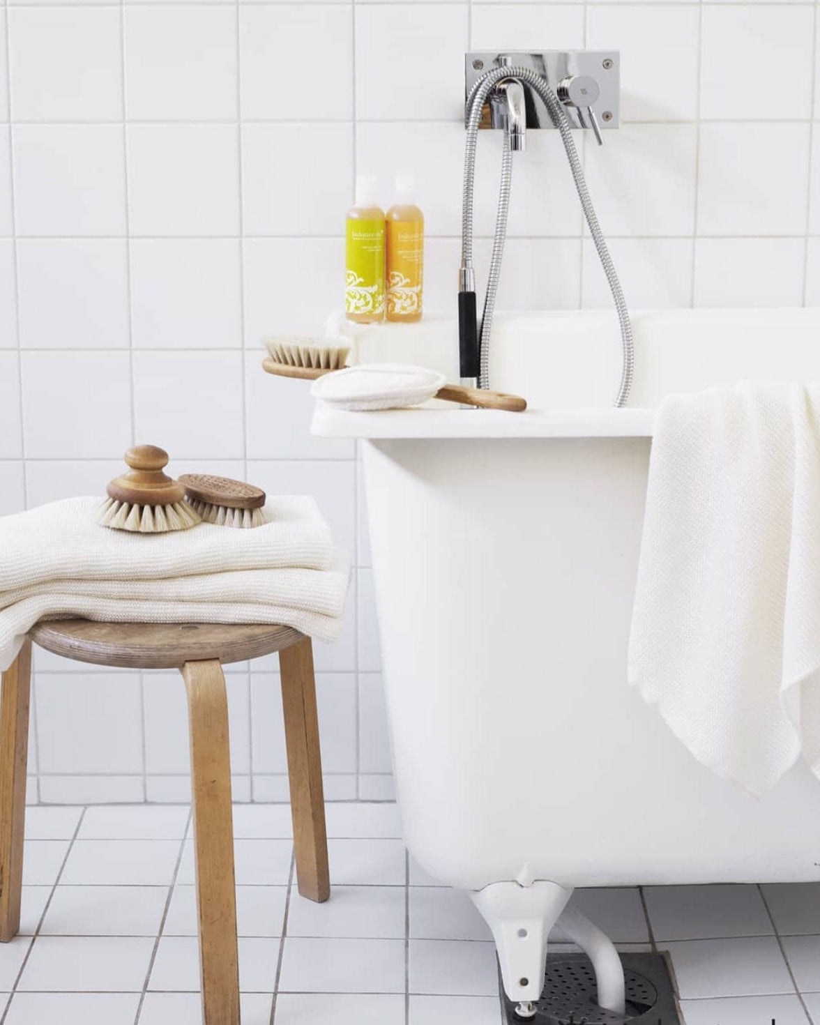 A white Iris Hantverk bathtub with a stool and towels.
