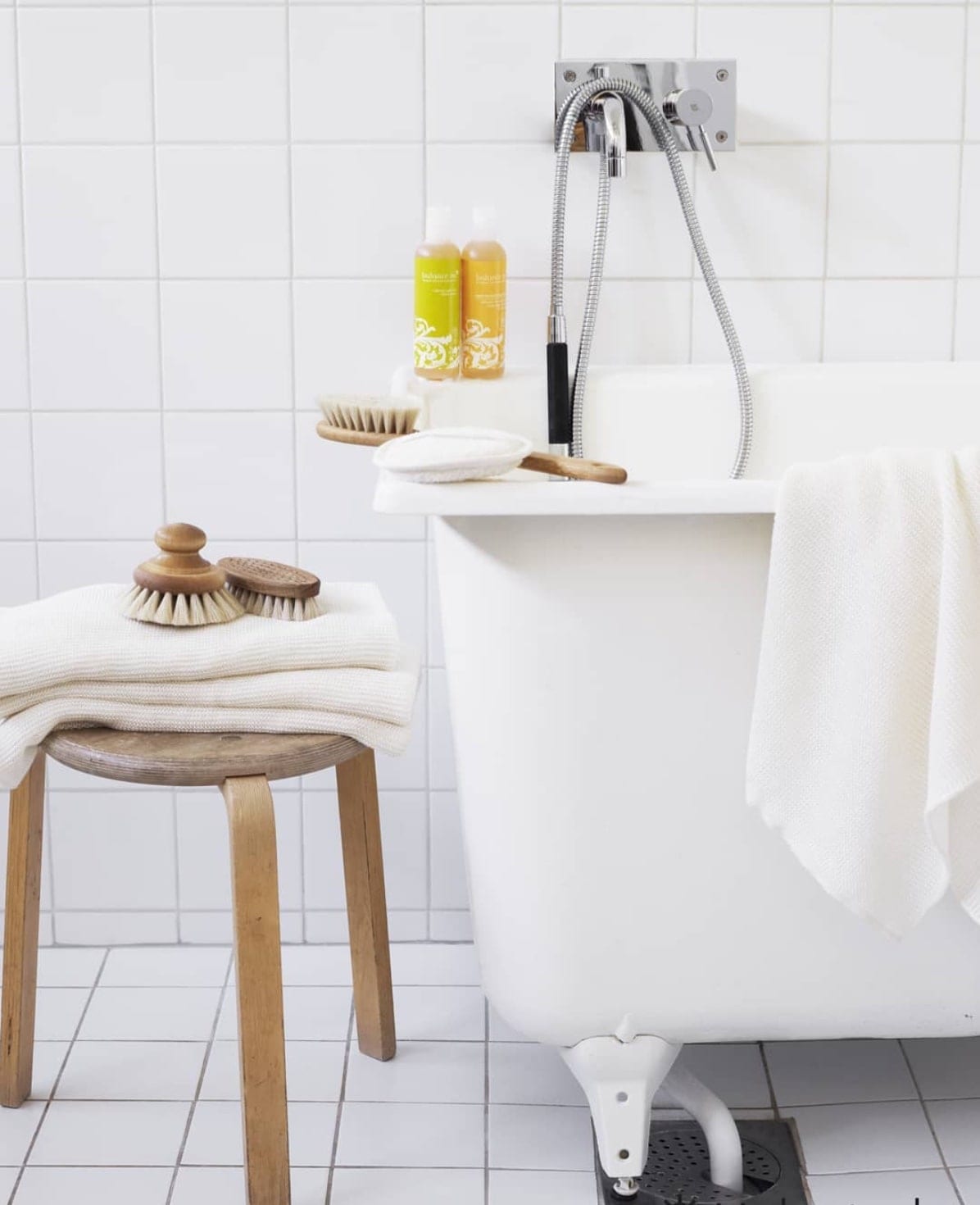 A white Iris Hantverk bathtub with a stool and towels.