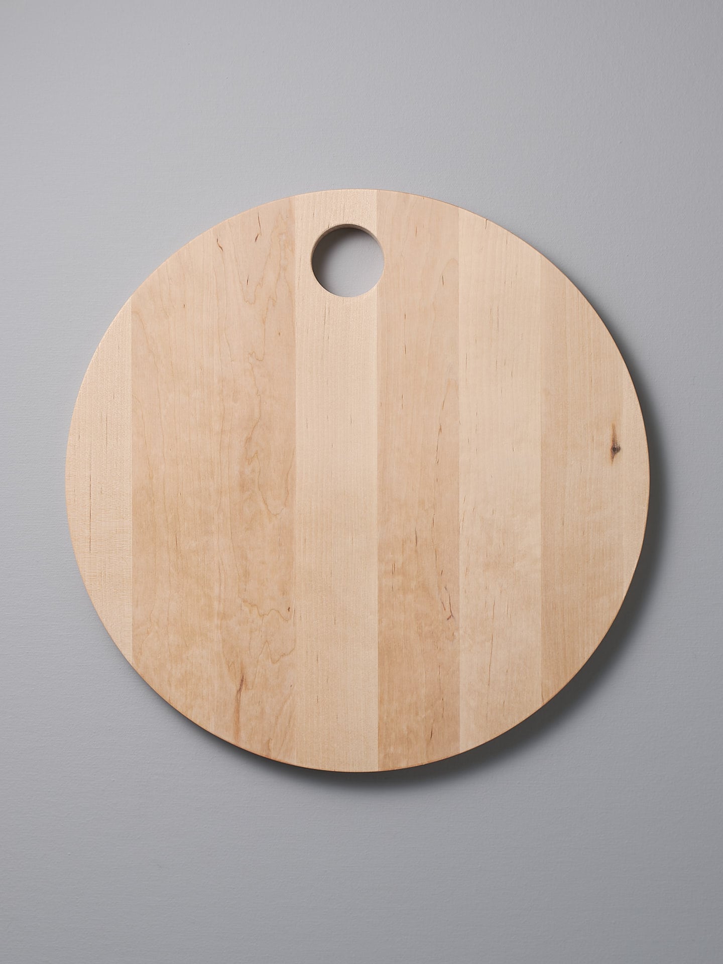 An Iris Hantverk Birch Chopping Board - Round with a hole at top.