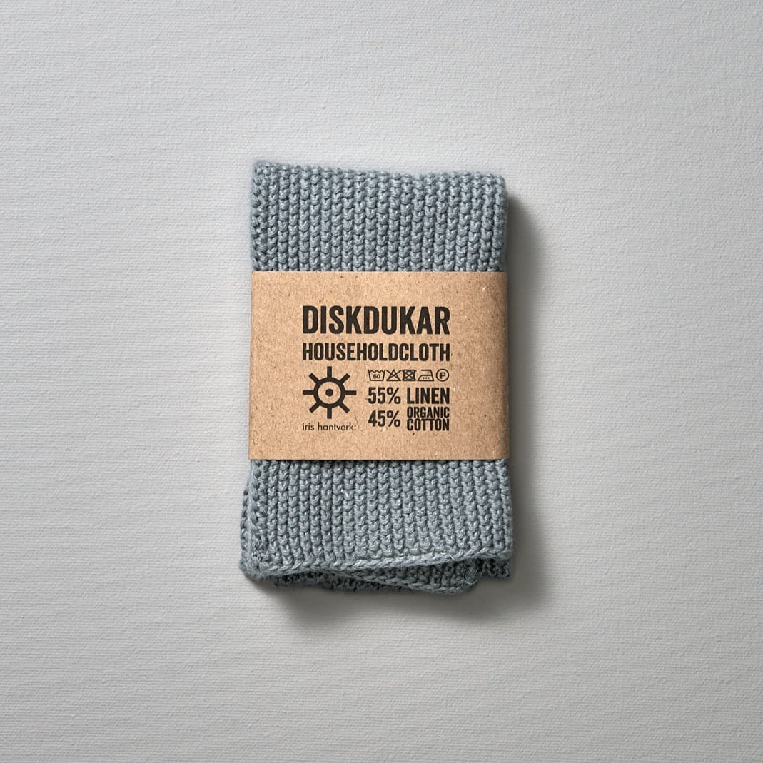 A blue Linen Household Cloth – Four Colours with the word disikurr on it, made from a linen/cotton blend for a household cloth that is absorbent, by Iris Hantverk.