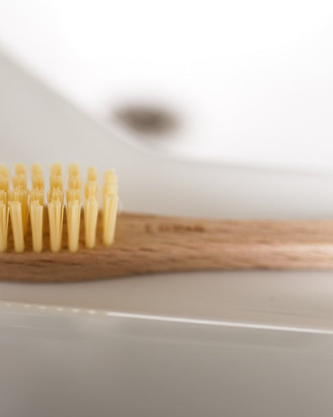 A wooden Iris Hantverk toothbrush next to a cardboard box.