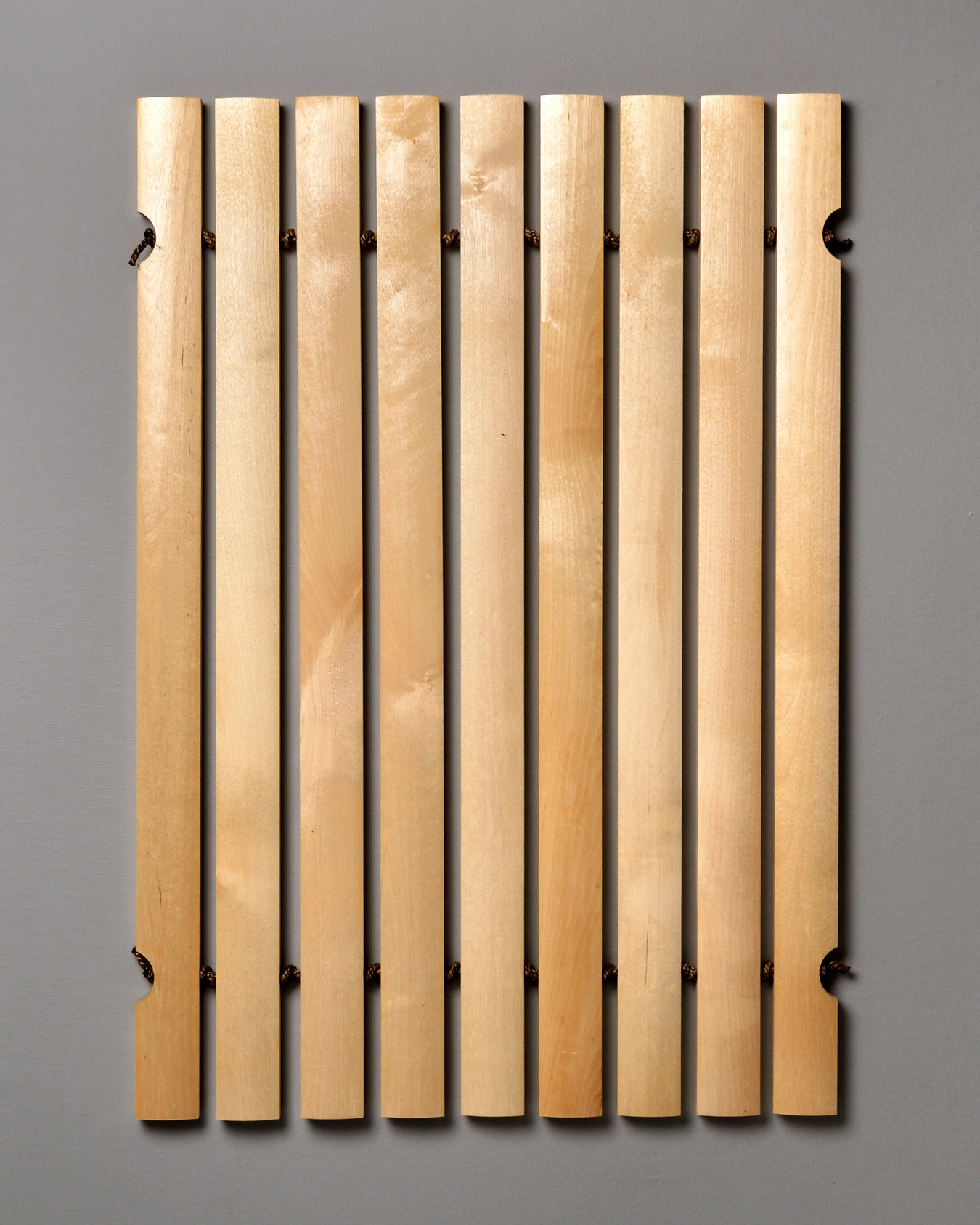 An Iris Hantverk Bathroom Mat with four wooden strips on a gray background.