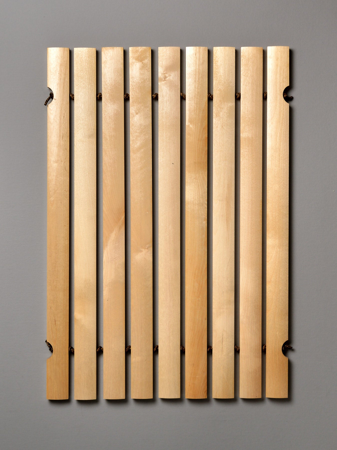 An Iris Hantverk Bathroom Mat with four wooden strips on a gray background.