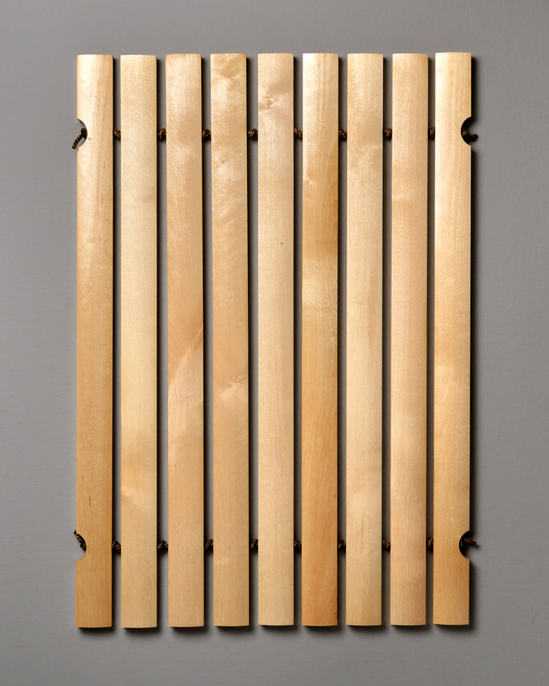 An Iris Hantverk Bathroom Mat with four wooden strips on a gray background.