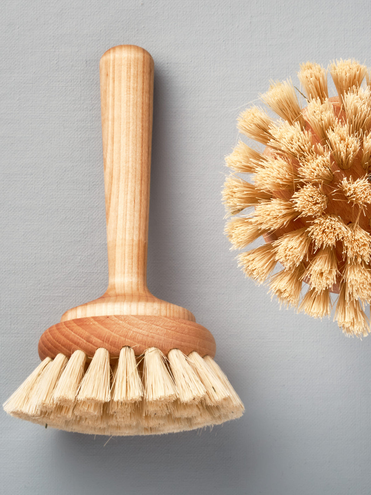 Two Iris Hantverk bathroom cleaning brushes next to each other on a grey background.