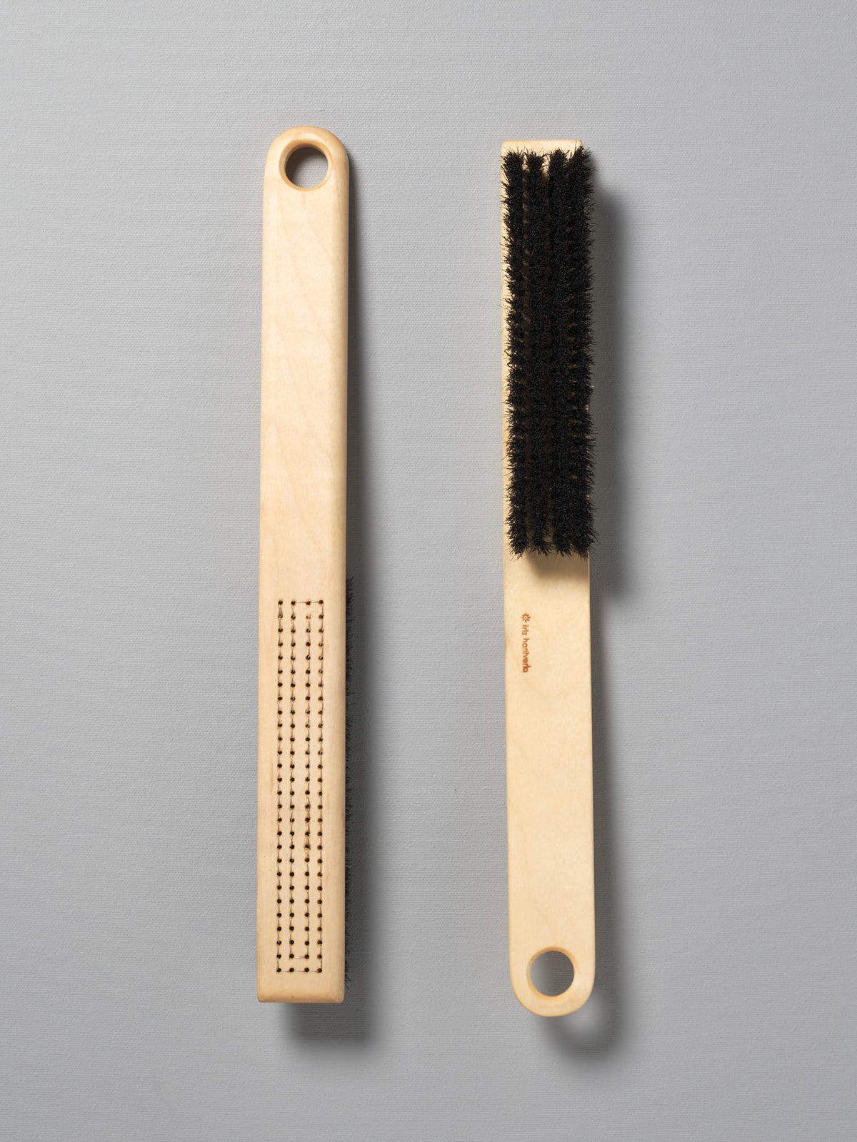 Two Iris Hantverk clothes brushes next to each other on a grey surface.