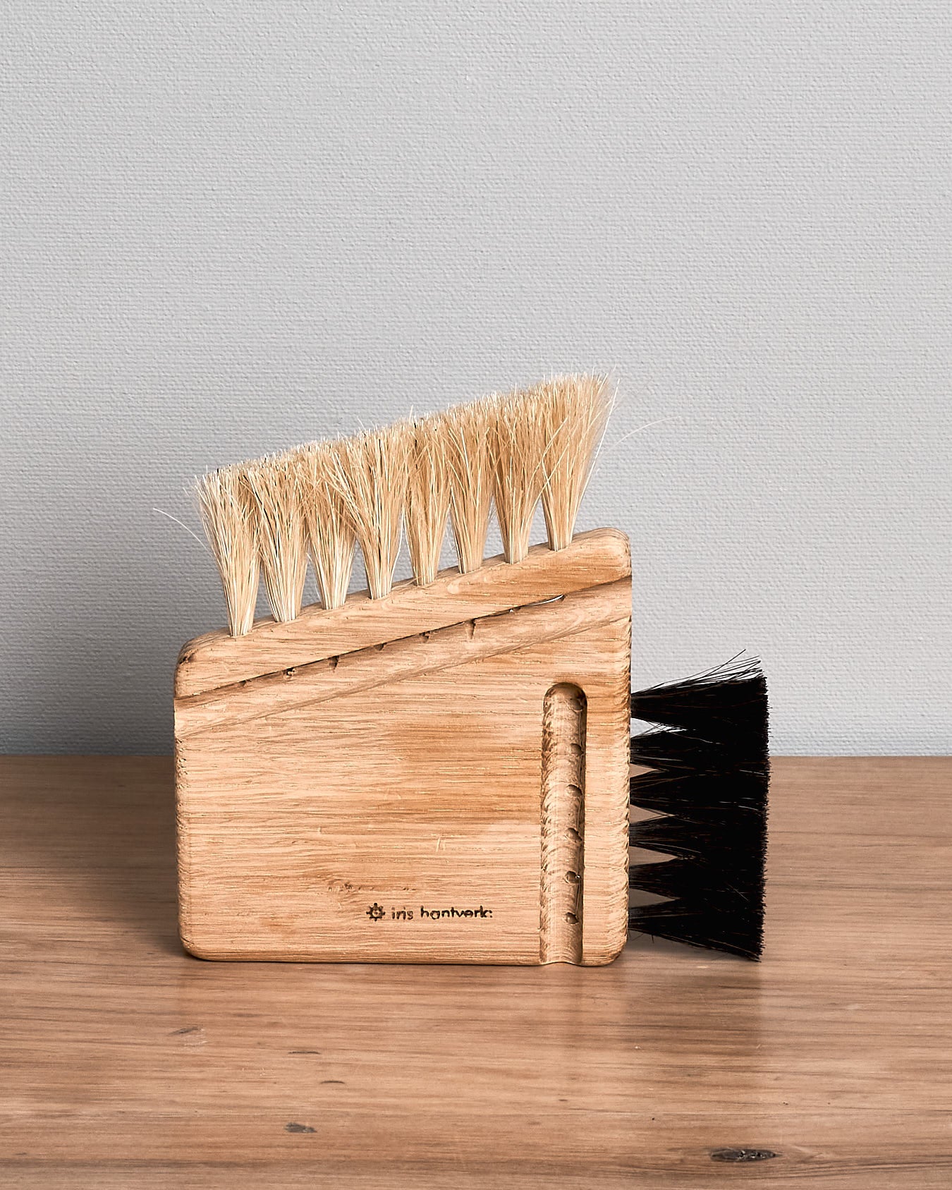An Iris Hantverk Computer Brush – Combi with black bristles sitting on top of a wooden table.