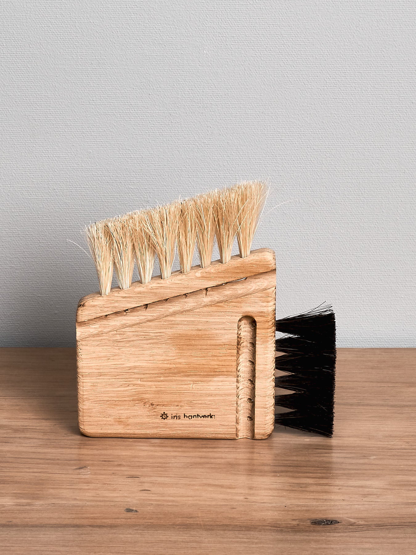 An Iris Hantverk Computer Brush – Combi with black bristles sitting on top of a wooden table.