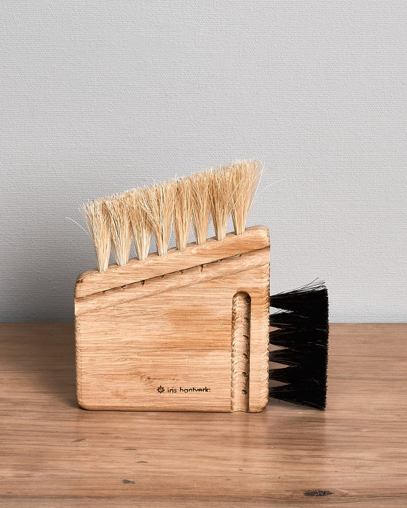 An Iris Hantverk Computer Brush – Combi with black bristles sitting on top of a wooden table.