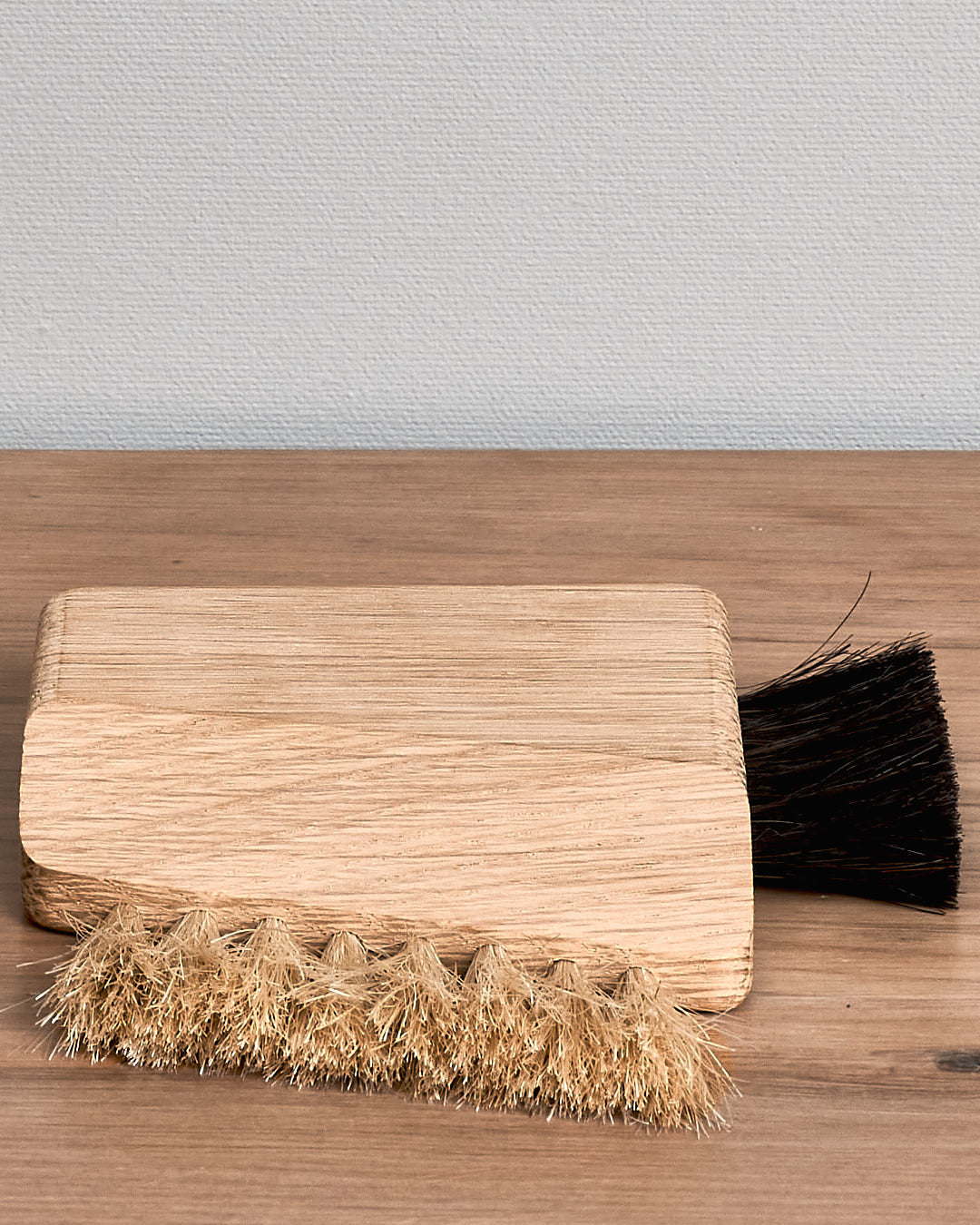 An Iris Hantverk Computer Brush – Combi with black bristles sitting on top of a wooden table.