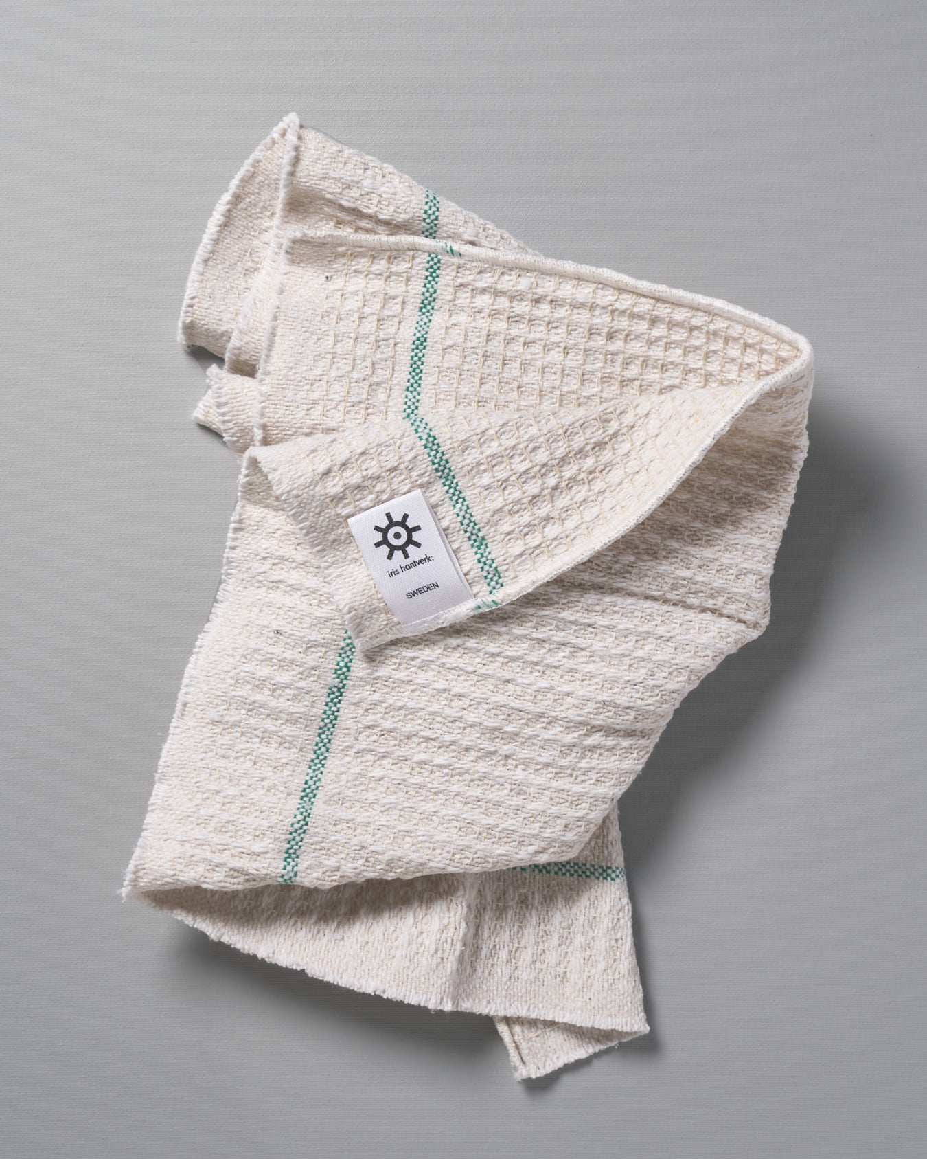 An Iris Hantverk white towel with a green stripe on it.