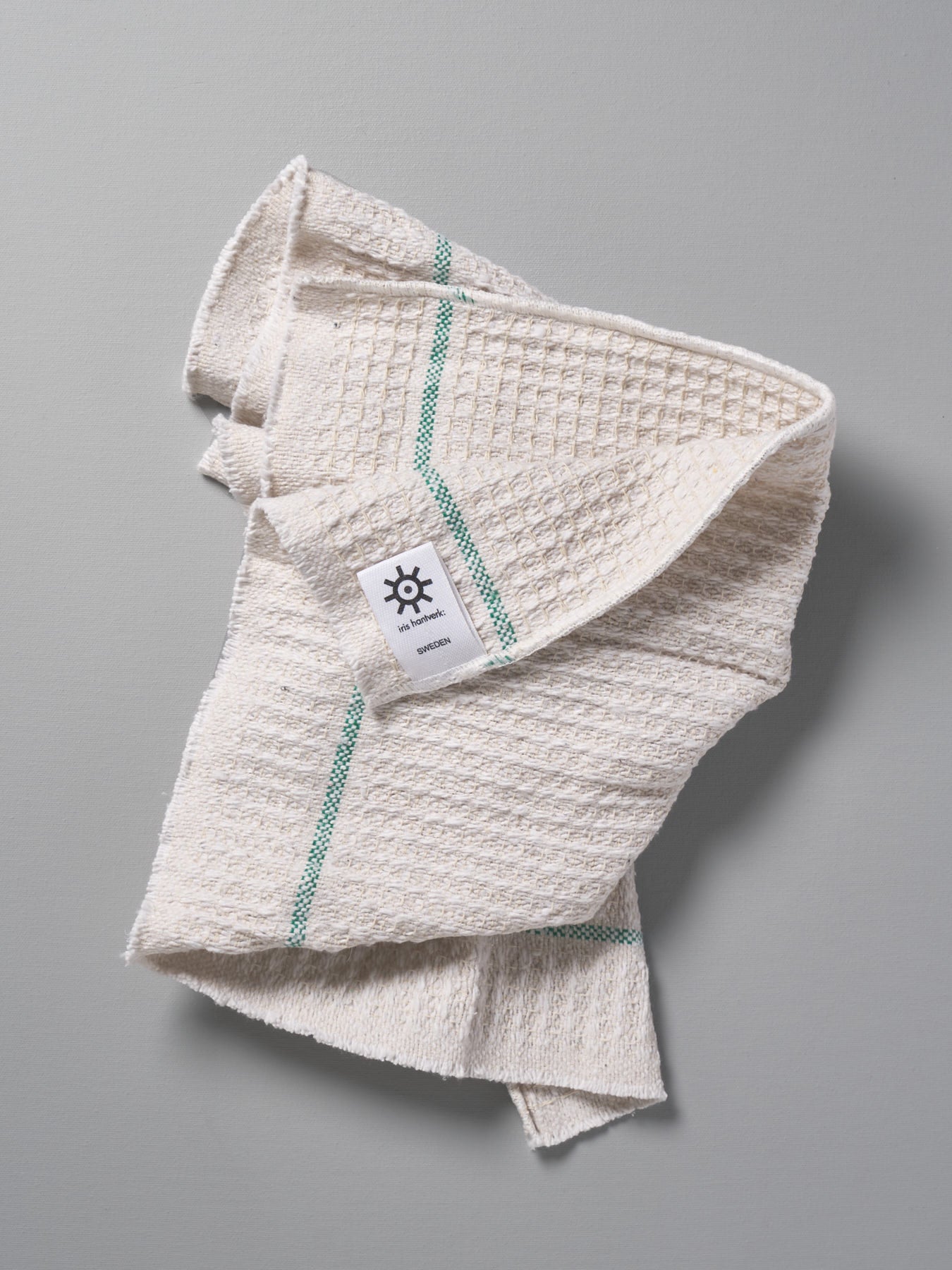 An Iris Hantverk white towel with a green stripe on it.