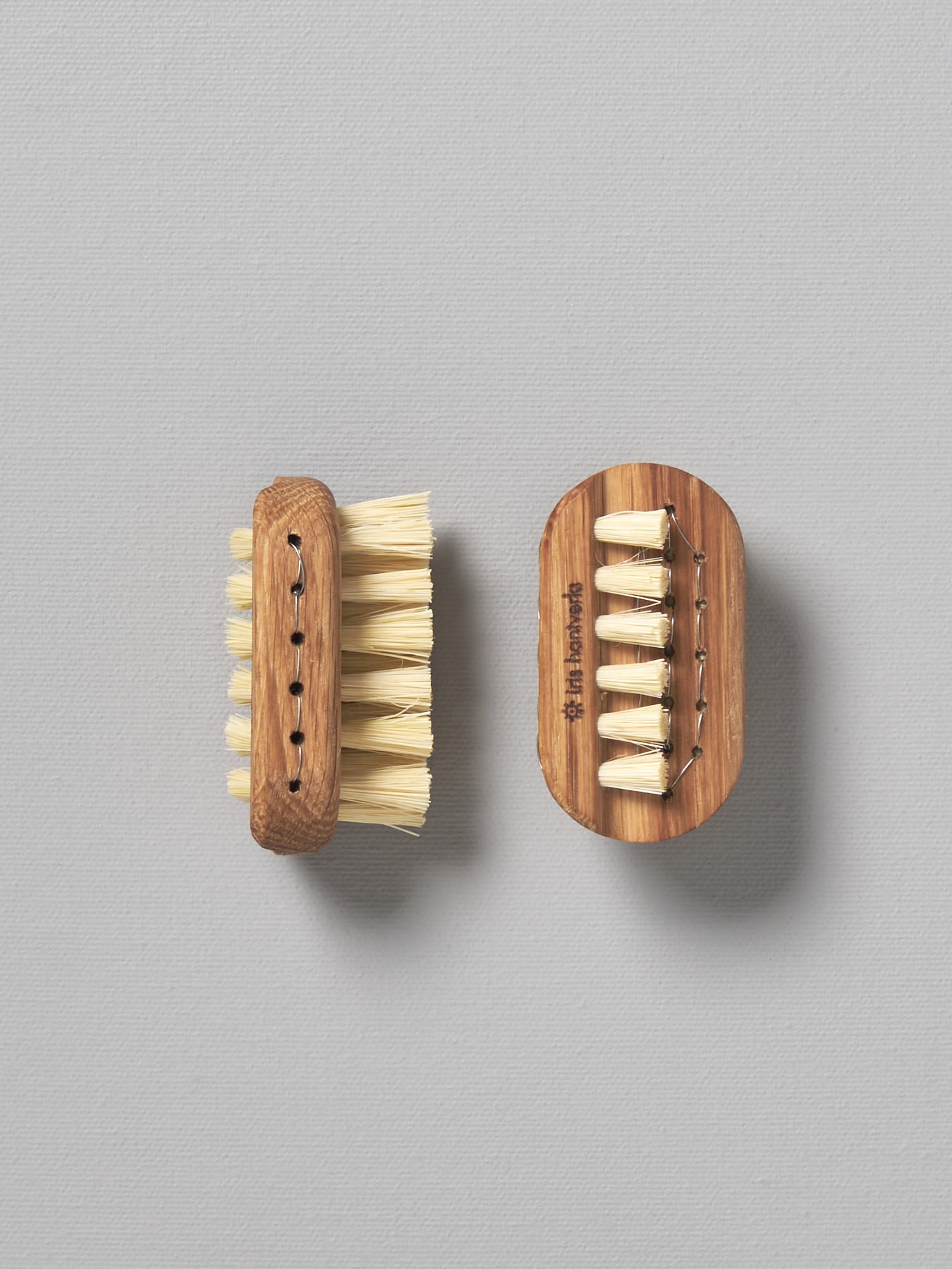 Two Iris Hantverk Nail Brushes - Small on a grey surface.