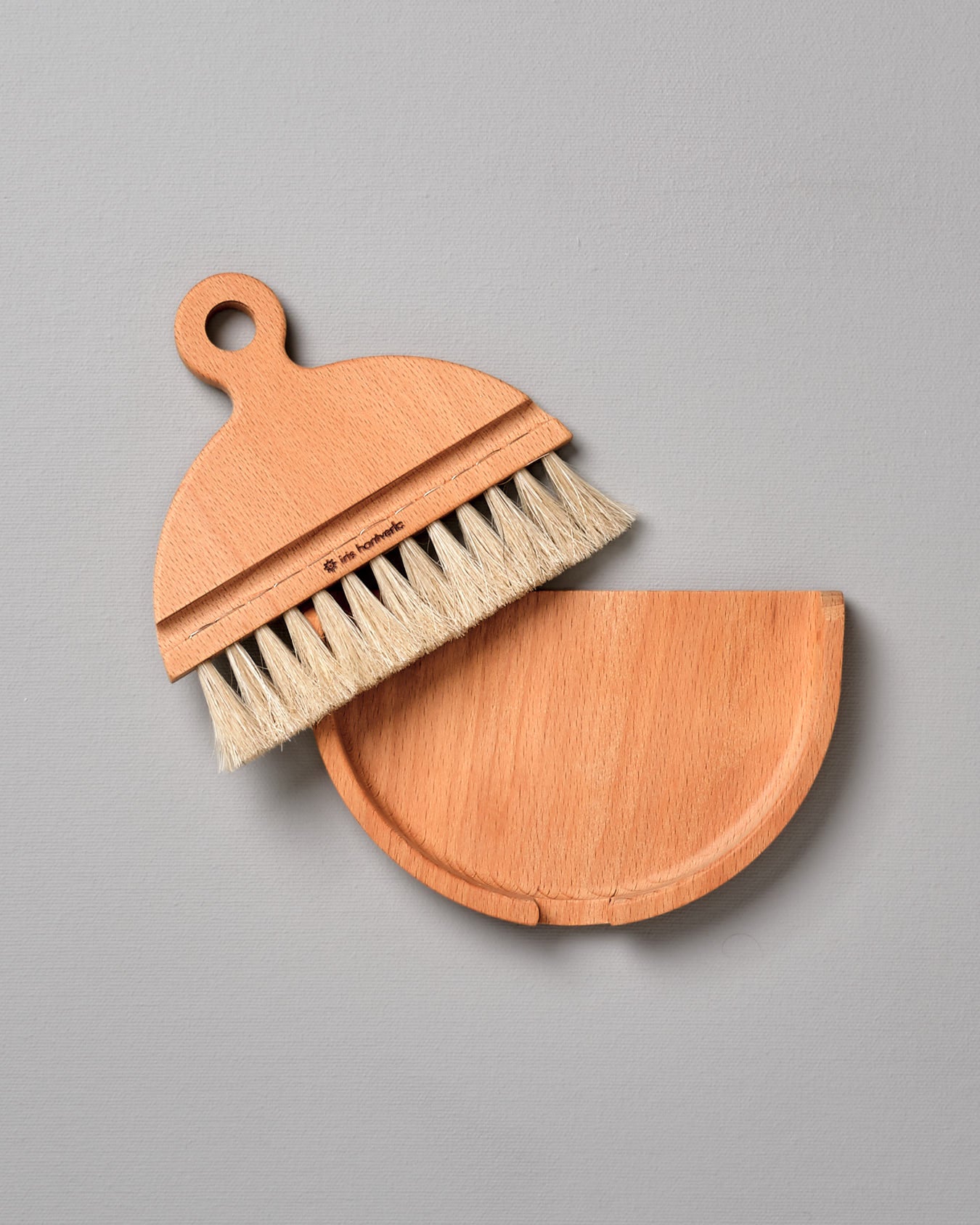 An Iris Hantverk Nesting Table Brush & Pan Set with bristles on a gray surface.