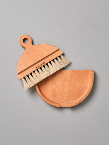 An Iris Hantverk Nesting Table Brush & Pan Set with bristles on a gray surface.