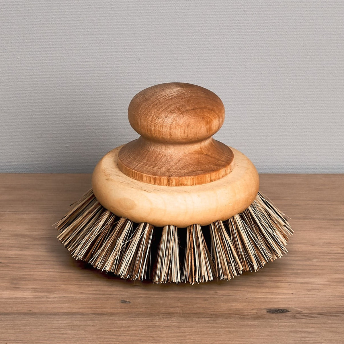 A Pot &amp; Pan Brush from Iris Hantverk sits on top of a wooden table.
