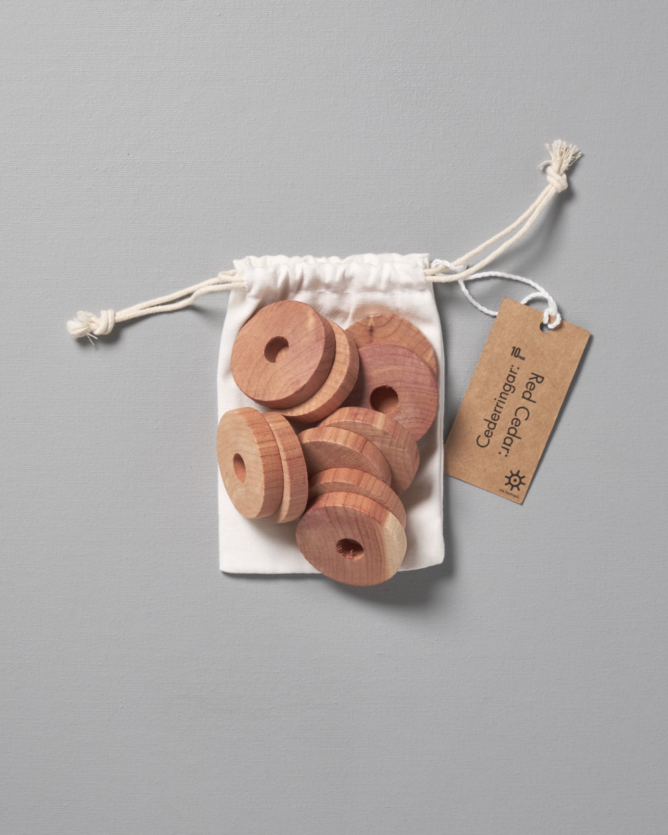 Red Cedar Rings – 10pcs by Iris Hantverk in a bag on a grey background.