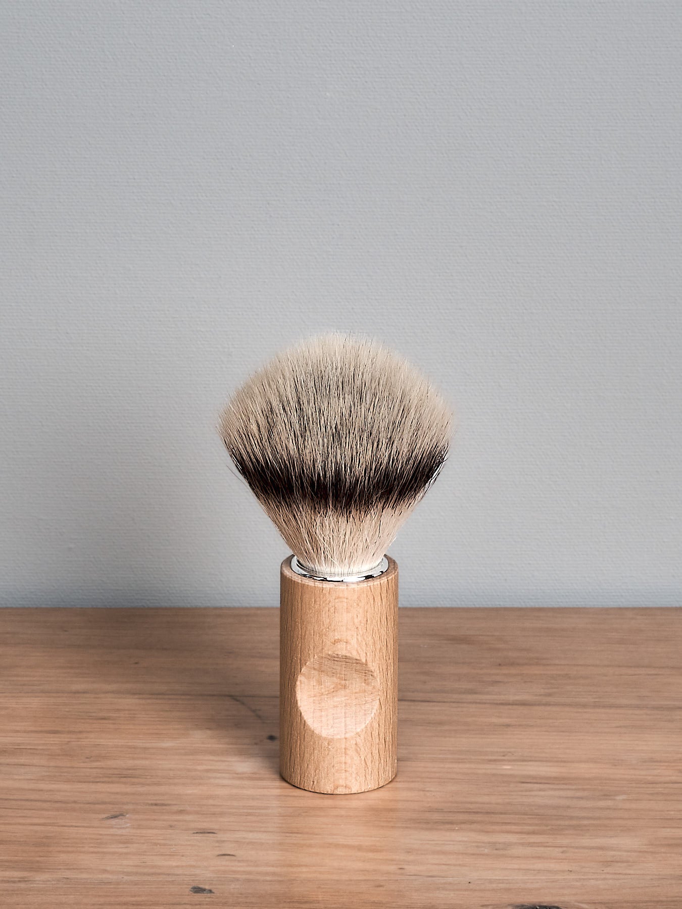 An Iris Hantverk Shaving Brush – Silver Tip sitting on top of a wooden stand.